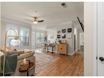 Cozy living room features hardwood floors, a ceiling fan, and large windows for natural light and a view to the dining area at 1821 Chatelain Way # 1821, Mount Pleasant, SC 29464