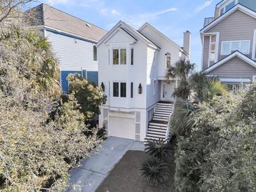 Beautiful white home with a garage and stairs leading to the front door surrounded by lush landscaping at 45 Ocean Point Dr, Isle of Palms, SC 29451