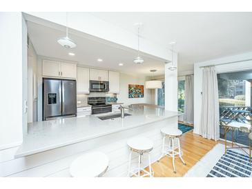 Bright kitchen featuring white cabinets, stainless appliances, stone countertops, and seating at the counter at 5541 Green Dolphin Way, Kiawah Island, SC 29455