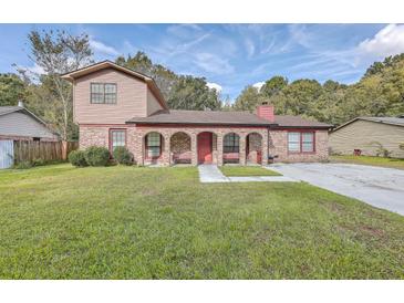 Charming brick home with an arched porch, benches, green lawn and a brick chimney at 7791 Peppercorn Ln, North Charleston, SC 29420