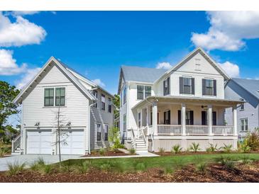 Charming white two-story home with a two-car garage and inviting front porch on a sunny day at 3019 Eventide Dr, Johns Island, SC 29455