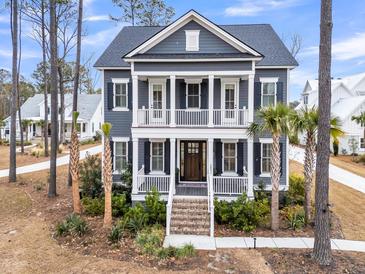 Inviting two-story home with a charming front porch, classic columns, and well-manicured landscaping and blue siding at 3851 Sawyers Island Dr, Mount Pleasant, SC 29466