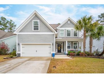 Charming two-story home with light gray siding, front porch, white trim, a two car garage and manicured front lawn at 5358 Birdie Ln, Hollywood, SC 29449