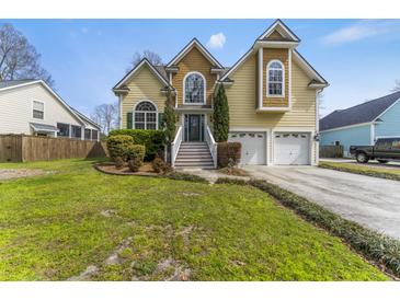 Charming two-story home featuring a well-manicured lawn, two-car garage, and inviting front entrance with mature trees at 644 Stoneboro Ct, Charleston, SC 29412