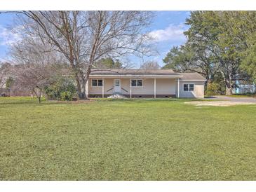 Charming single-story home with a covered porch and a spacious front yard, perfect for outdoor activities at 106 Mayrant St, Summerville, SC 29483