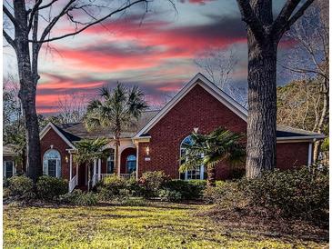 Charming brick home with manicured lawn, lush landscaping, and vibrant plants at sunset at 1407 Congressional Blvd, Summerville, SC 29483