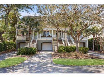 Charming townhomes featuring garages, elevated entryways, and lush landscaping create a welcoming facade at 1902 Long Bend Dr # 1B, Seabrook Island, SC 29455