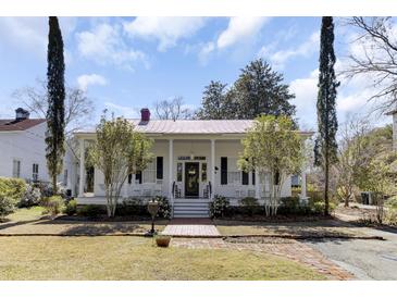 Charming white home with red roof, brick walkway and front porch at 214 E Doty Ave, Summerville, SC 29483