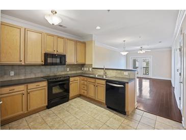 Traditional kitchen with wood cabinets, black appliances, and a view into the adjacent living room at 2244 Ashley Crossing Dr # 1236, Charleston, SC 29414
