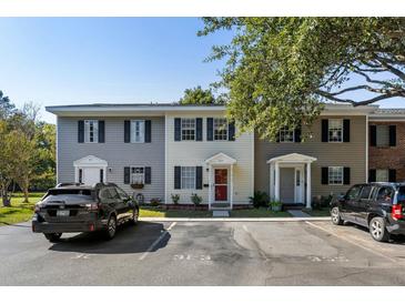 A cozy two-story townhome showcasing a red door, black shutters, and parking spaces in front of the unit at 303 Lakeside Dr # C-2, Mount Pleasant, SC 29464