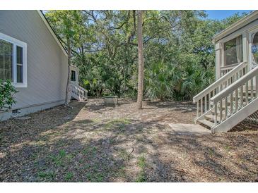 Relaxing backyard with lush greenery featuring a central tree and stairway to the right at 433 Double Eagle Trace, Seabrook Island, SC 29455