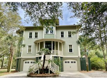 Inviting exterior of home featuring double garages, palm trees, and a staircase to a welcoming front porch at 6021 Jibe Ct, Awendaw, SC 29429