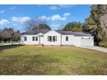 Charming single-story home with a well-maintained lawn, attached garage, and classic white siding at 1409 Main St, Bonneau, SC 29431