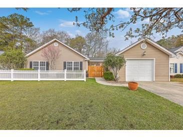 Charming single-story home features a manicured lawn, white picket fence and attached garage at 143 Moon Dance Ln, Summerville, SC 29483