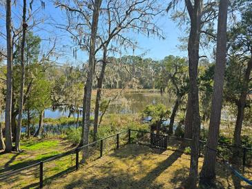 Private backyard with fence overlooking a tranquil river and lush, mature trees with Spanish moss at 8585 Refuge Pointe Cir, North Charleston, SC 29420