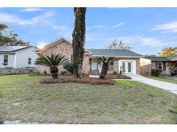 Charming brick home with manicured lawn, beautiful landscaping, and a light blue door at 1393 Secessionville Rd, James Island, SC 29412