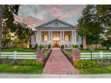 Stunning two-story home featuring classic architectural details, a brick walkway, and an expansive front lawn at sunset at 1714 Middle St, Sullivans Island, SC 29482