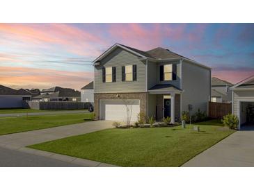 Charming home exterior featuring a well-manicured lawn, two-car garage, and traditional architectural details at sunset at 202 N Light Way, Summerville, SC 29486