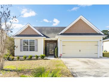 Inviting single-story home with a two-car garage, manicured landscaping, and appealing architectural details at 7649 Fayetteville Rd, North Charleston, SC 29418