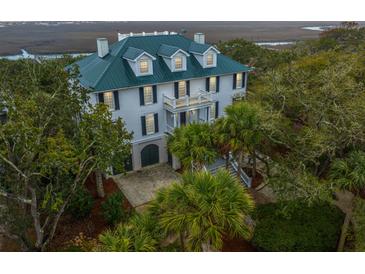 Stately two-story home with a green metal roof and grand entrance surrounded by mature trees and lush landscaping at 944 Hammocks Way, Edisto Island, SC 29438