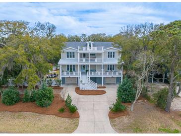 Stunning two-story home with double porches, mature landscaping, and a spacious driveway nestled in a lush, tree-filled yard at 3204 Waterway Blvd, Isle of Palms, SC 29451