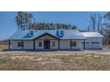 Charming home featuring a blue metal roof, white siding and covered porch, perfect for curb appeal at 709 Oakridge View Trl, Ridgeville, SC 29472