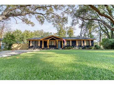 Charming single-story home features a beautifully manicured lawn, a dark brick facade, and light stained wood accents at 841 Fred St, Charleston, SC 29412