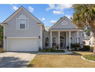 Charming home featuring a two-car garage, manicured lawn, and inviting front porch with white columns at 9394 Harroway Rd, Summerville, SC 29485
