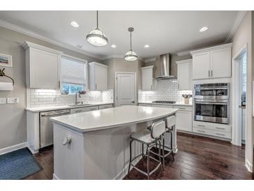 Bright kitchen boasts white cabinets, subway tile backsplash, stainless appliances, and a large island with pendant lighting at 1644 Fishbone Dr, Johns Island, SC 29455