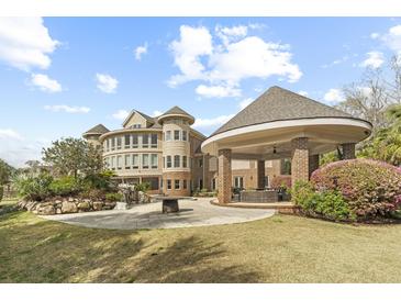 Stunning backyard with covered patio, outdoor fire pit, and meticulously manicured landscaping creating a luxurious outdoor space at 4202 Links Ct, North Charleston, SC 29420