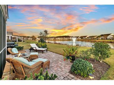 Inviting brick patio with fire pit and lakeside view and fountain, perfect for outdoor relaxation and entertaining at 514 Eastern Isle Ave, Summerville, SC 29486