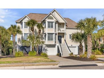 Charming coastal home featuring double garages, palm trees, and a welcoming staircase to the front door at 65 Ocean Point Dr, Isle of Palms, SC 29451