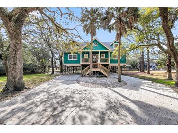 Charming raised beach home with a spacious driveway, mature trees, and a welcoming front porch at 1009 Seacrest Ln, Folly Beach, SC 29439