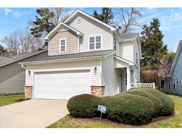 Charming two-story home features a garage and a welcoming front yard with lush greenery at 104 Chemistry Cir, Ladson, SC 29456