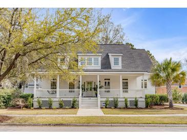 Charming two-story home featuring a welcoming white porch, lush landscaping, and classic architectural details at 124 Beresford Creek St, Charleston, SC 29492