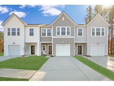 New townhome exteriors with white and gray siding, attached garages, and neatly manicured lawn at 5569 Ruby Falls Drive Ln, North Charleston, SC 29420