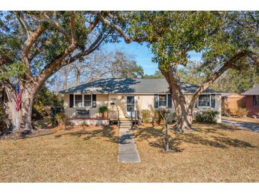 Charming single-story home with a well-manicured lawn and mature trees shading the front yard at 728 N Godfrey Park Pl, Charleston, SC 29407