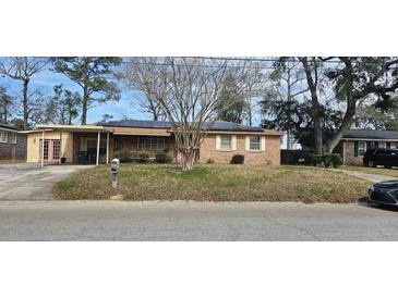 Charming single-story brick home featuring solar panels, a covered carport, and a traditional mailbox at 7660 Allwood Ave, North Charleston, SC 29418