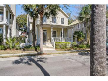 Charming two-story home features a welcoming front porch and well-maintained landscaping, enhanced by mature palm trees at 102 Barnaby St, Charleston, SC 29492