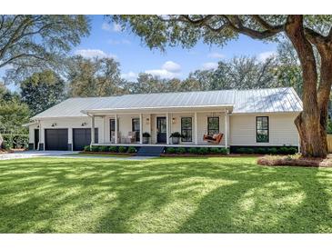 Charming single-story home with a metal roof, inviting front porch with a swing, and a well-manicured lawn at 299 Bampfield Dr, Mount Pleasant, SC 29464