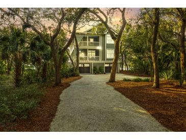 Charming multi-story home with double garage nestled among mature trees and manicured landscaping with a gravel driveway at 3034 Maritime Forest Dr, Johns Island, SC 29455