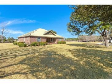 A charming single-story brick home on a large lot with a metal roof and lush, green landscaping at 732 Lindhaven Dr, Pineville, SC 29468
