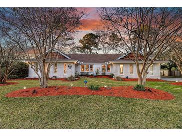 Charming brick home featuring landscaped yard with mature trees and colorful mulch at 1522 N Pinebark Ln, Charleston, SC 29407