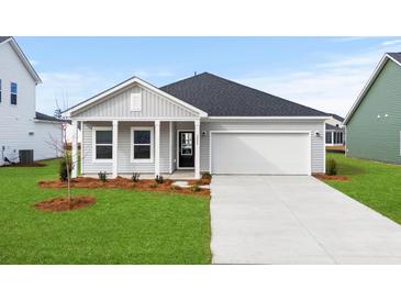 Charming single-Gathering home showcasing a well-manicured lawn, a two-car garage, and a welcoming front porch at 657 Cottage Landing Dr, Summerville, SC 29485