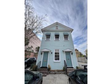 Charming two-story house with a light blue facade, white trim, and matching blue doors and awnings at 101 Queen St, Charleston, SC 29401