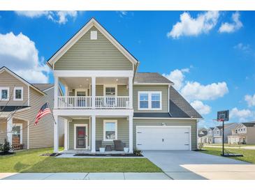 Charming two-story home featuring a welcoming front porch, attached garage, and well-manicured lawn at 131 Swaying Palm Dr, Summerville, SC 29485
