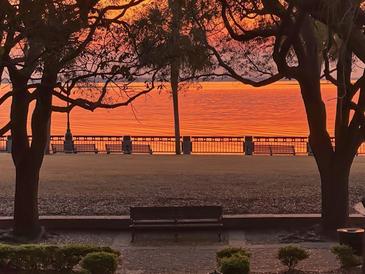 Serene waterfront view featuring benches along the promenade at sunset or sunrise at 32 Prioleau St # N, Charleston, SC 29401