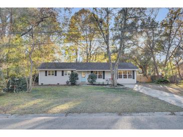 Charming single-story home with a blue door, well-manicured lawn and mature trees, creating a welcoming curb appeal at 402 Corey Blvd, Summerville, SC 29483