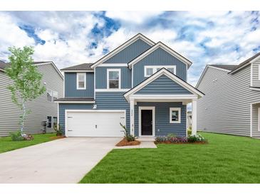 Charming two-story home features a blue exterior, well-manicured lawn, and an attached white two-car garage at 588 Red Monarch Way, Moncks Corner, SC 29461