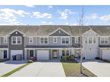 Charming townhouse with a two-car garage, complemented by a well-maintained front yard on a sunny day at 9712 Transplanter Cir, Ladson, SC 29456
